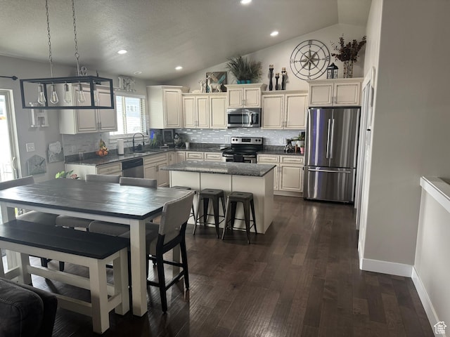 kitchen featuring a kitchen island, appliances with stainless steel finishes, vaulted ceiling, and backsplash