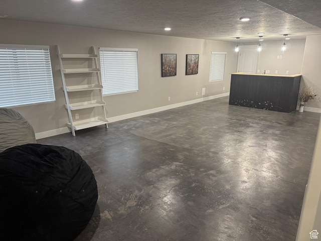 basement featuring a textured ceiling, baseboards, bar area, and recessed lighting