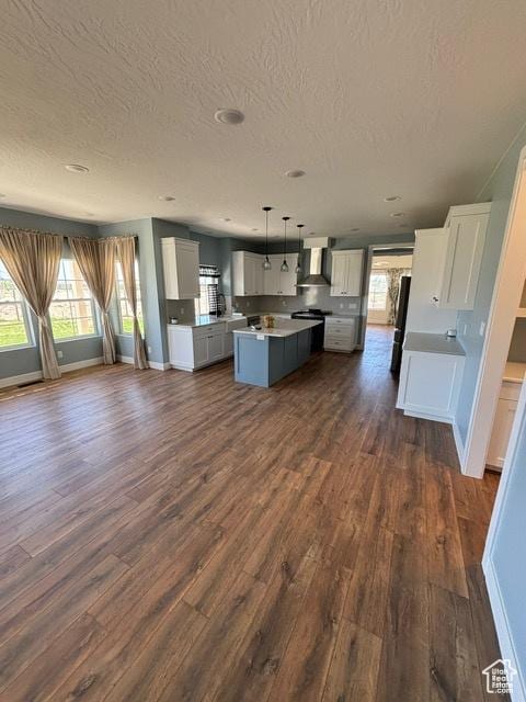 2577 W 5300 N Unit 11, Cedar City, UT 84721 - kitchen featuring wall chimney exhaust hood, a textured ceiling, a kitchen island, dark wood-style flooring, and open floor plan