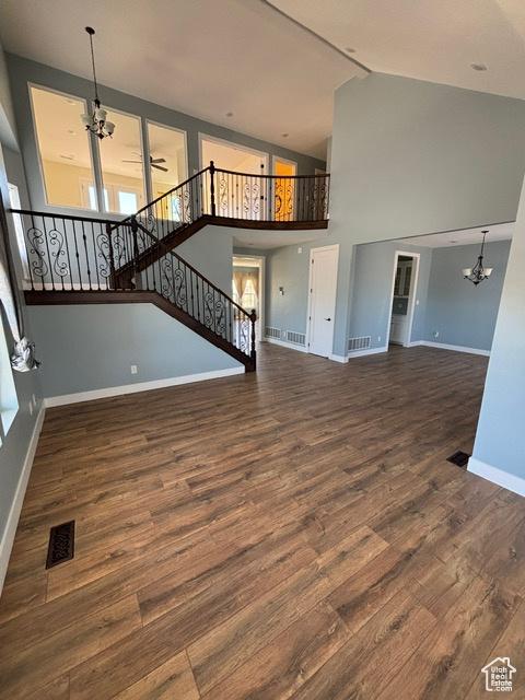 2577 W 5300 N Unit 11, Cedar City, UT 84721 - unfurnished living room featuring a chandelier, wood finished floors, baseboards, high vaulted ceiling, and stairway
