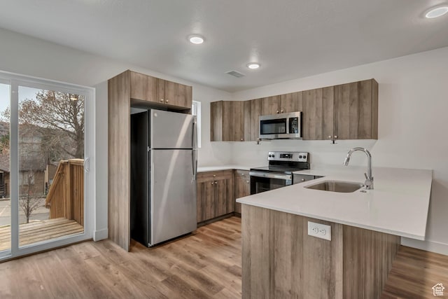 1679 S 1355 E Unit A21, Ogden, UT 84404 - kitchen featuring stainless steel appliances, a sink, a peninsula, light countertops, and brown cabinets