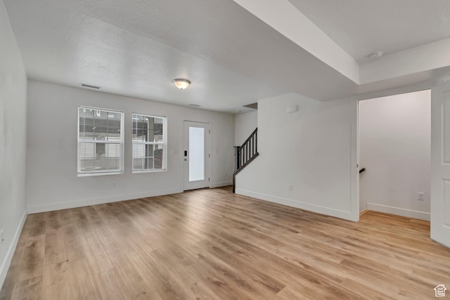 1679 S 1355 E Unit A21, Ogden, UT 84404 - unfurnished living room featuring light wood finished floors, baseboards, and stairs