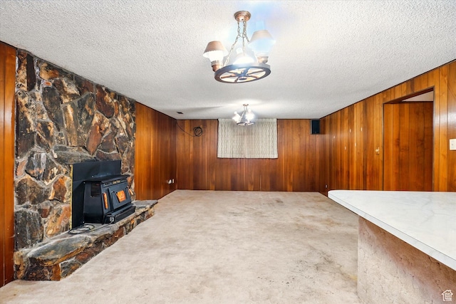 490 W 300 N, Smithfield, UT 84335 - unfurnished living room featuring a wood stove, a textured ceiling, wood walls, and carpet floors
