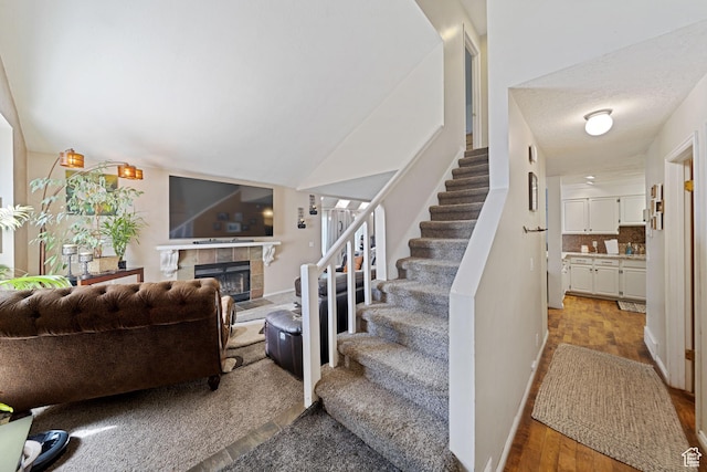 staircase featuring a fireplace, wood finished floors, and baseboards