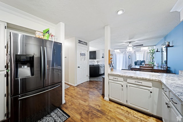 kitchen featuring stainless steel fridge with ice dispenser, a ceiling fan, light wood-style flooring, white cabinetry, and light stone counters