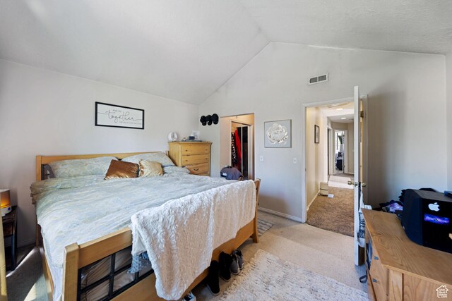 bedroom with light colored carpet, vaulted ceiling, a closet, and baseboards