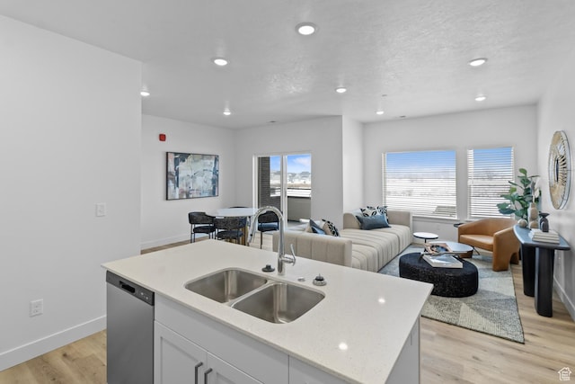 3085 S 225 W Unit 204, Nibley, UT 84321 - kitchen featuring stainless steel dishwasher, baseboards, a sink, open floor plan, and a center island with sink
