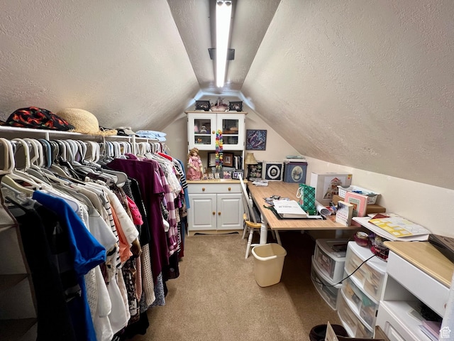 walk in closet with vaulted ceiling and light colored carpet