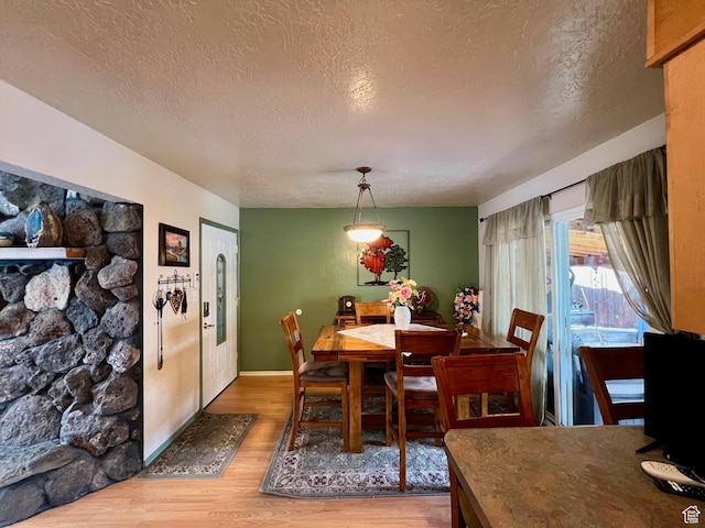 dining area featuring baseboards, a textured ceiling, and wood finished floors