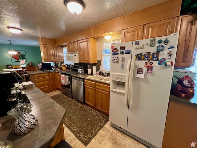 kitchen featuring a textured ceiling, white appliances, plenty of natural light, and a sink