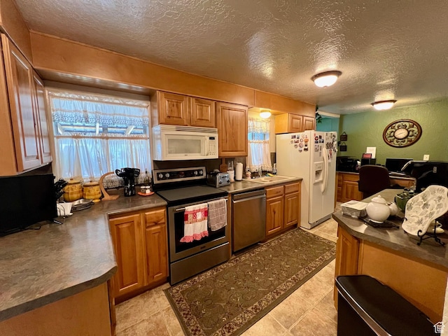 kitchen featuring brown cabinetry, dark countertops, stainless steel appliances, and a textured ceiling