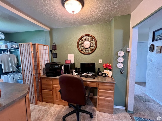 office space with a textured ceiling, visible vents, and a textured wall