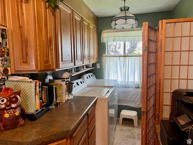 washroom with a textured ceiling, cabinet space, and independent washer and dryer
