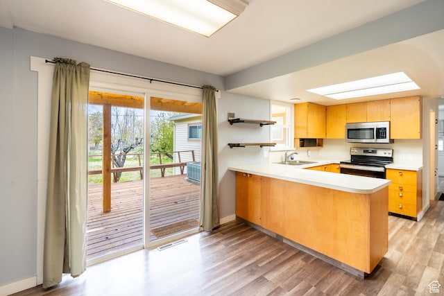 kitchen featuring a sink, stainless steel appliances, open shelves, visible vents, and light wood-style floors