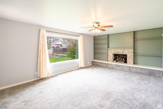 unfurnished living room featuring carpet, visible vents, baseboards, and ceiling fan