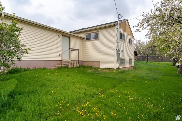 rear view of property with a lawn and entry steps