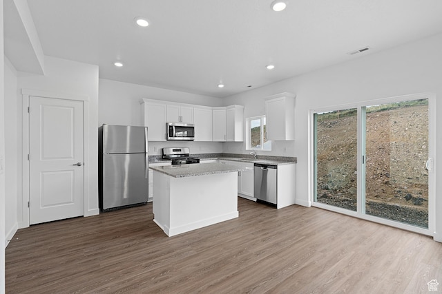 kitchen with dark wood-style flooring, stainless steel appliances, visible vents, and white cabinets