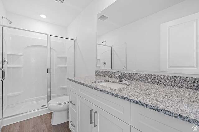 full bathroom featuring a stall shower, vanity, toilet, and wood finished floors