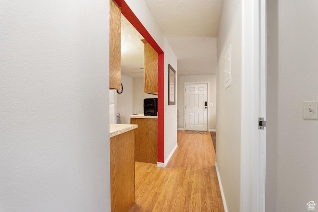hall featuring baseboards and light wood-type flooring