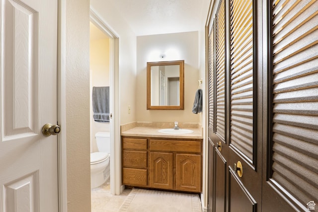 bathroom with toilet, tile patterned floors, and vanity