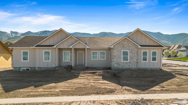 view of front of property featuring roof with shingles, stone siding, a mountain view, and board and batten siding