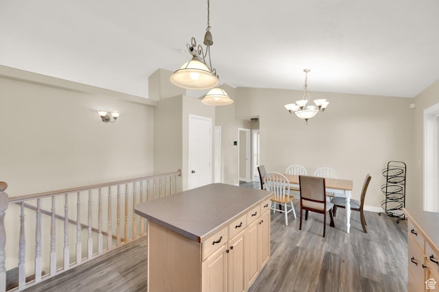 kitchen featuring baseboards, vaulted ceiling, light wood finished floors, a center island, and a notable chandelier