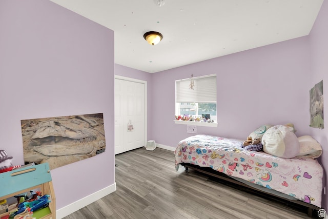 bedroom with baseboards, a closet, and wood finished floors
