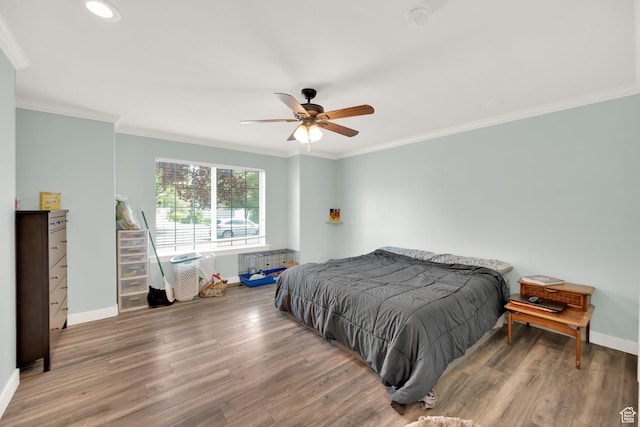 bedroom with crown molding, baseboards, and wood finished floors