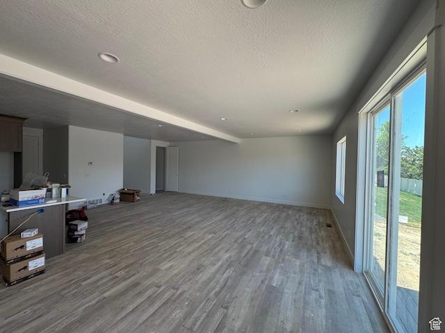 2831 S Allison Way Unit 110, Syracuse, UT 84075 - unfurnished living room featuring wood finished floors, a textured ceiling, baseboards, and recessed lighting