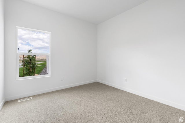 carpeted empty room featuring baseboards and visible vents