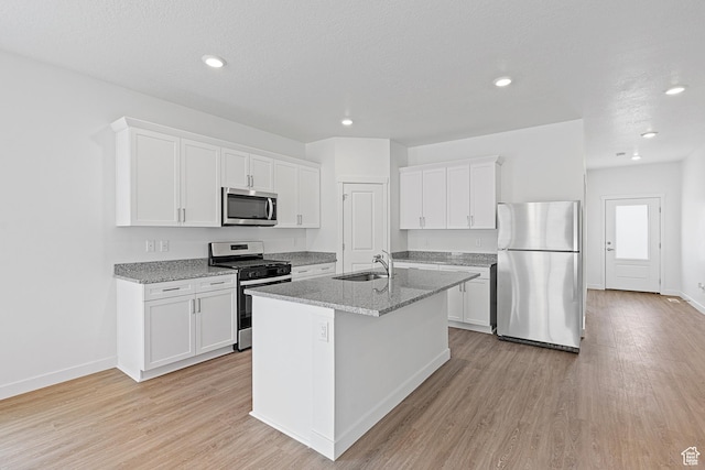 kitchen with white cabinets, light wood-style floors, stainless steel appliances, and a sink