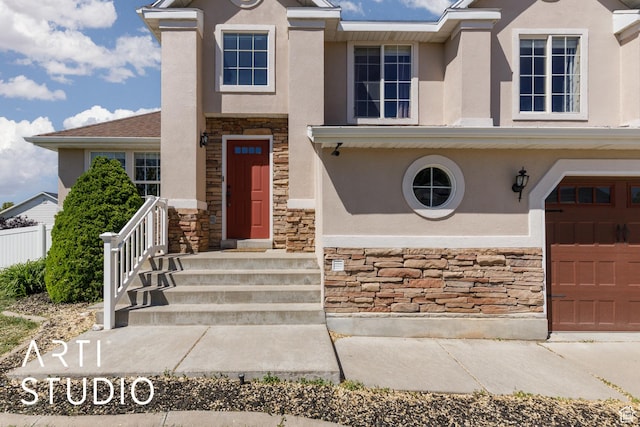 view of front of home featuring stone siding, stucco siding, and a garage