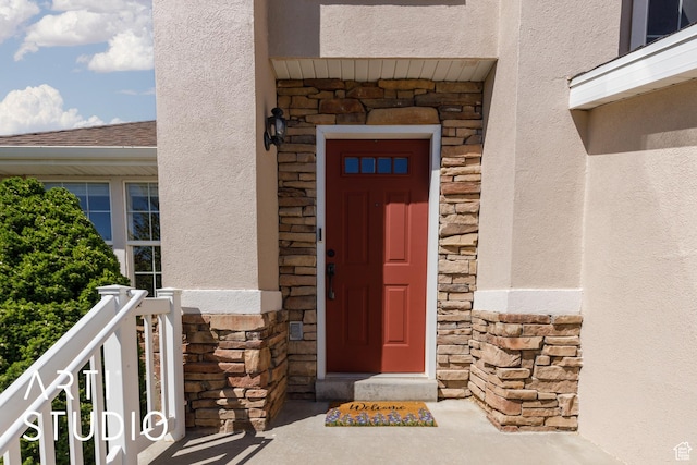 property entrance featuring stone siding and stucco siding