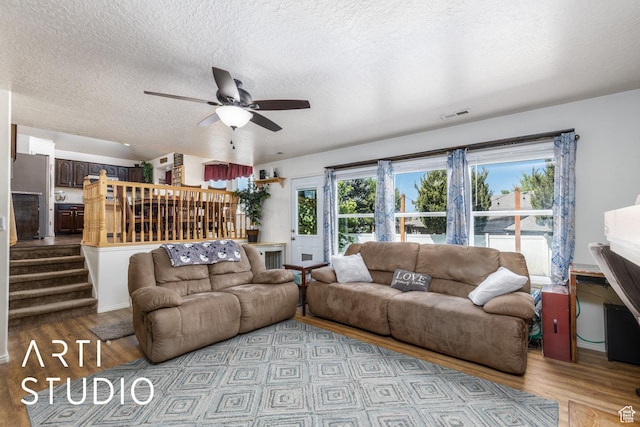 living room with stairway, ceiling fan, a textured ceiling, and wood finished floors