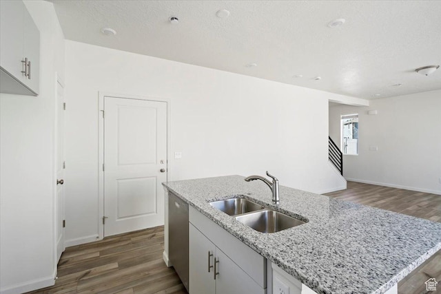 353 N Colonnade Rd Unit 1007, Saratoga Springs, UT 84045 - kitchen with stainless steel dishwasher, light stone counters, a sink, wood finished floors, and a kitchen island with sink