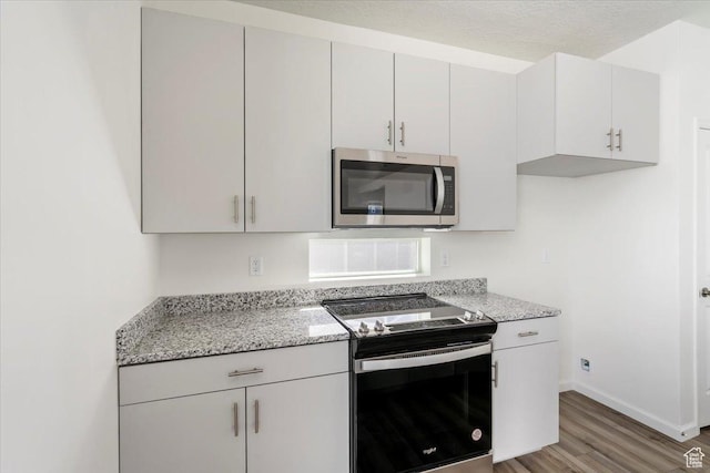 353 N Colonnade Rd Unit 1007, Saratoga Springs, UT 84045 - kitchen featuring light wood-type flooring, baseboards, light stone countertops, and appliances with stainless steel finishes