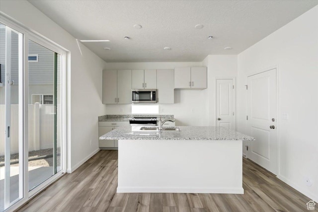 353 N Colonnade Rd Unit 1007, Saratoga Springs, UT 84045 - kitchen with a sink, appliances with stainless steel finishes, light stone counters, baseboards, and light wood-style floors