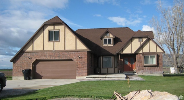 18235 N 4400 W, Fielding, UT 84311 - tudor-style house featuring concrete driveway, brick siding, a front yard, a garage, and stucco siding
