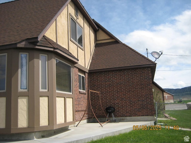 18235 N 4400 W, Fielding, UT 84311 - view of side of property with stucco siding, fence, a shingled roof, brick siding, and a patio area