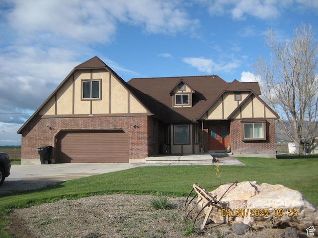 tudor house featuring brick siding, an attached garage, stucco siding, concrete driveway, and a front yard