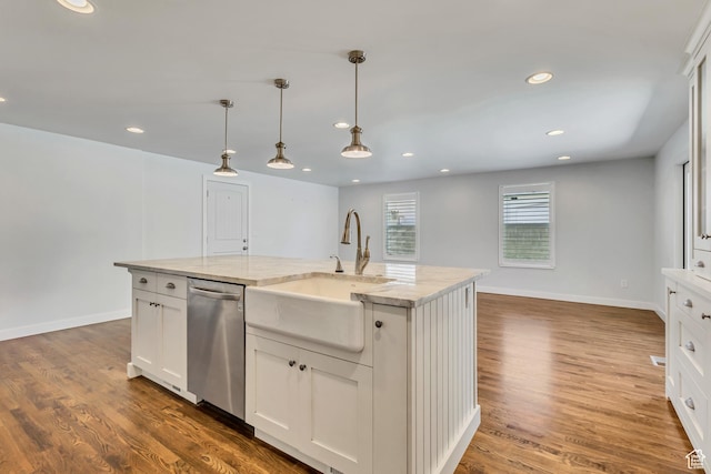 kitchen with pendant lighting, stainless steel dishwasher, a sink, wood finished floors, and white cabinets