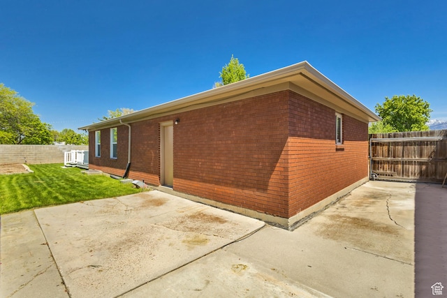 view of home's exterior with fence, a patio area, and brick siding
