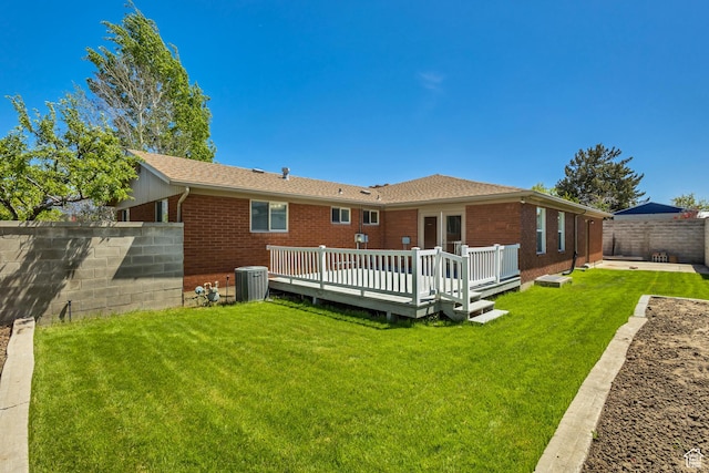 rear view of property featuring a lawn, central air condition unit, brick siding, and a fenced backyard