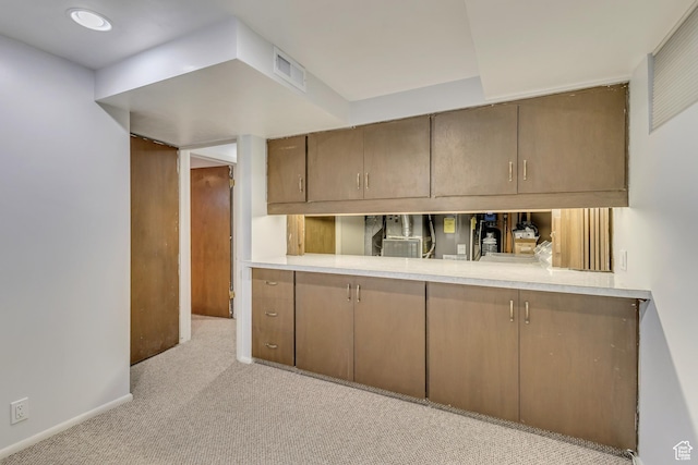 kitchen with baseboards, light countertops, visible vents, and light colored carpet