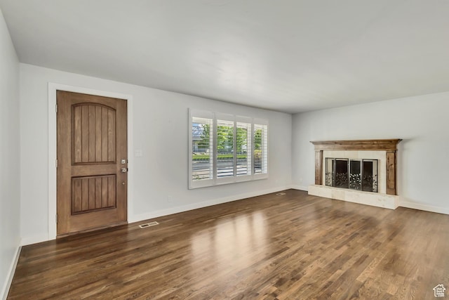 unfurnished living room featuring baseboards, a high end fireplace, visible vents, and wood finished floors