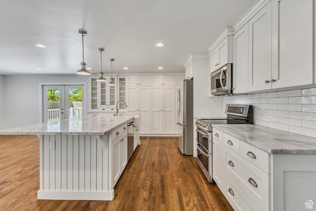 kitchen with an island with sink, white cabinetry, backsplash, appliances with stainless steel finishes, and dark wood-style floors
