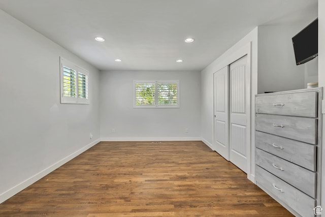 unfurnished bedroom featuring baseboards, dark wood-style flooring, a closet, and recessed lighting