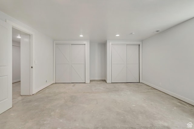 unfurnished bedroom with two closets, visible vents, concrete flooring, baseboards, and recessed lighting