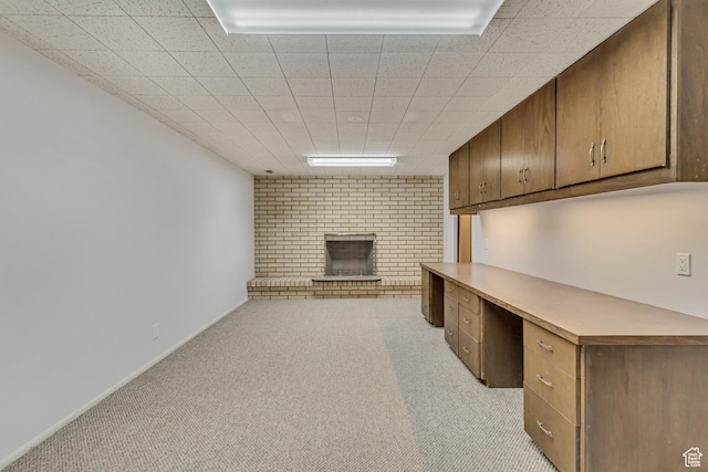 unfurnished office with a fireplace, built in study area, light carpet, and baseboards