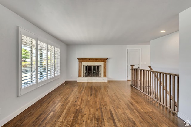 unfurnished living room with a high end fireplace, baseboards, dark wood-type flooring, and recessed lighting